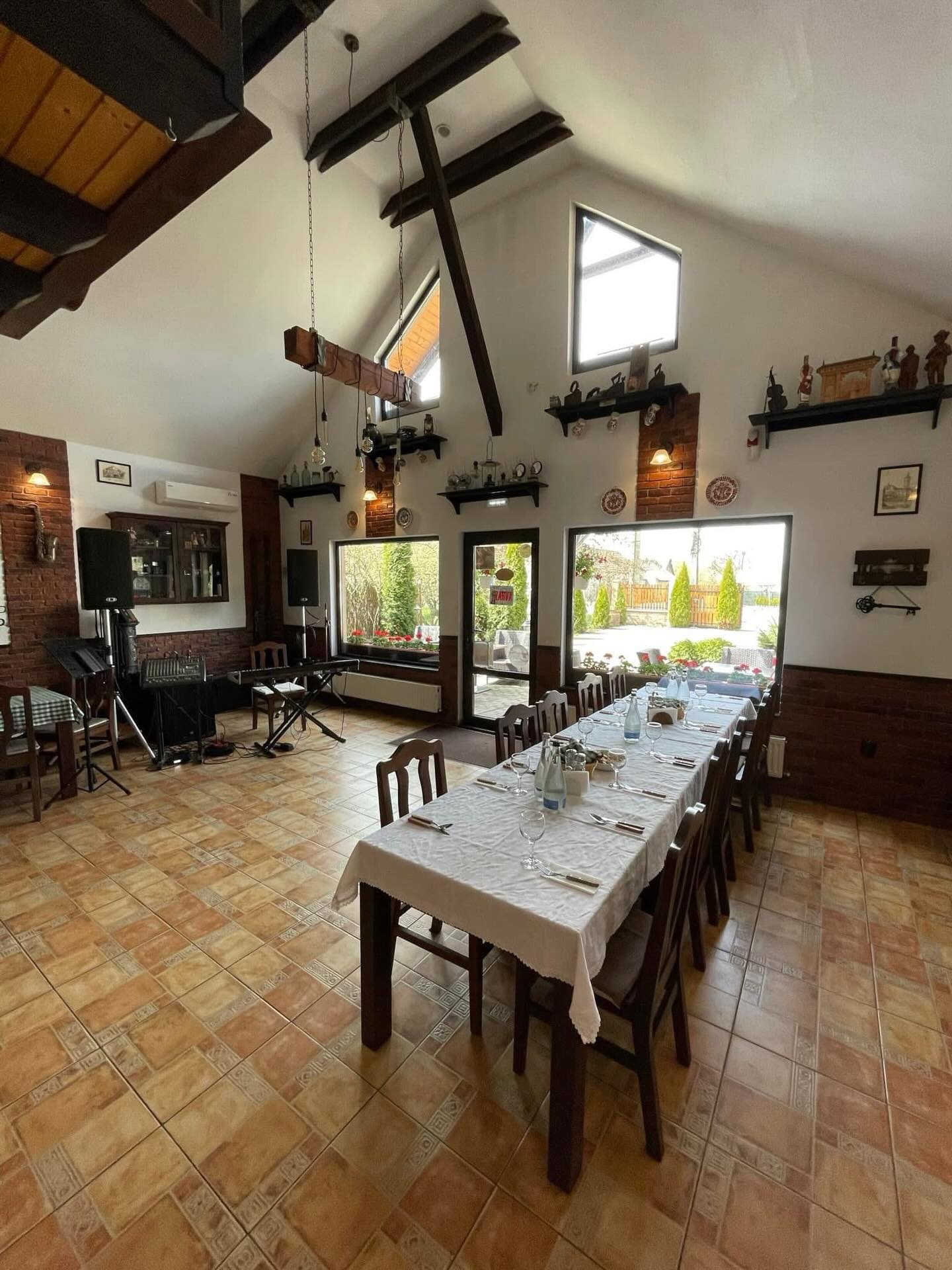 Sala de evenimente — tavan înalt cu grinzi de lemn, masă lungă